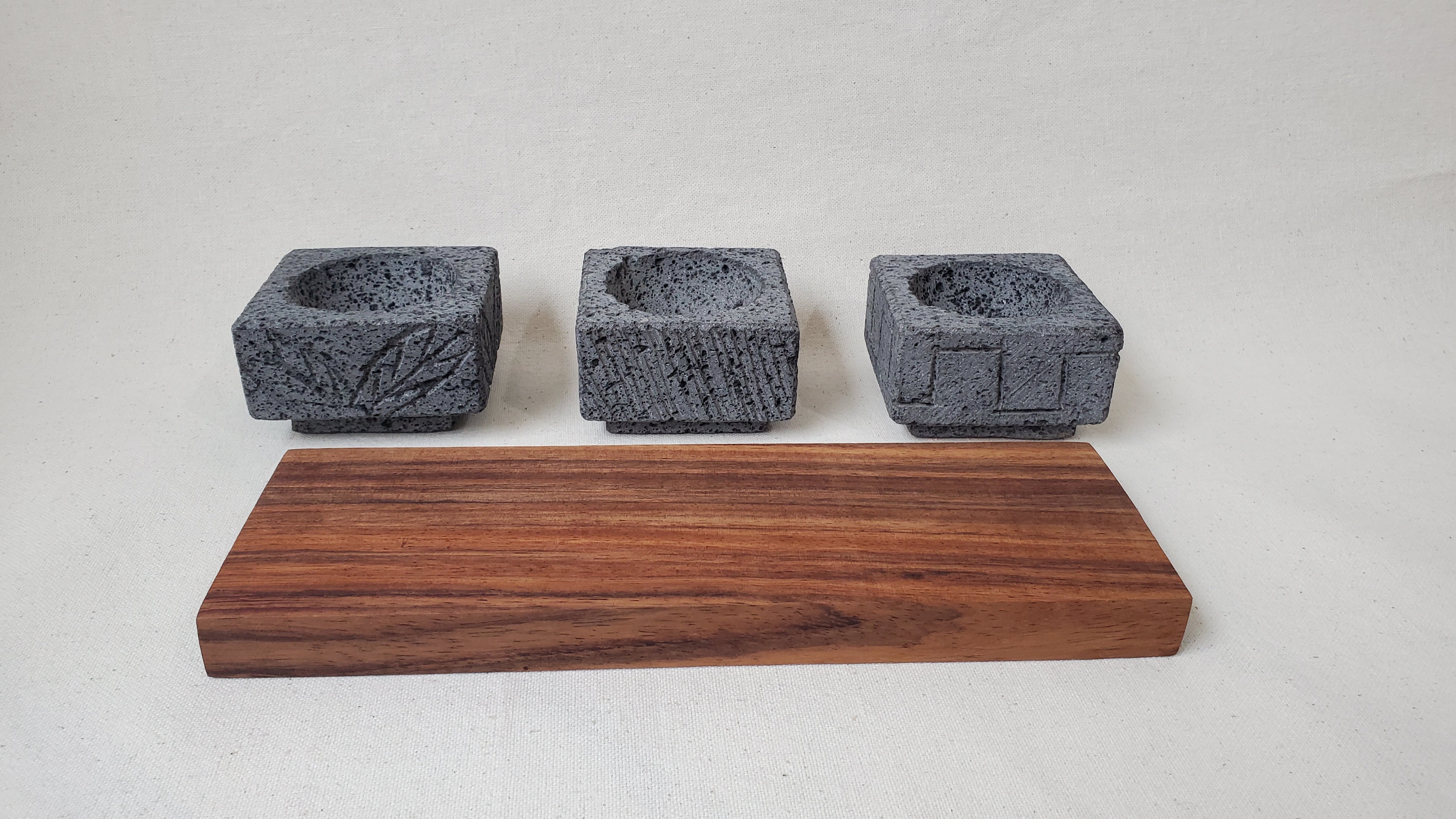 Three Square Serving Bowls on a Rectangle Wooden Base. Made of Basalt Lava Rock Volcanic Stone. Handmade in Mexico using traditional techniques. We hand finish, package, and ship from the USA. Buy now at www.felipeandgrace.com.
