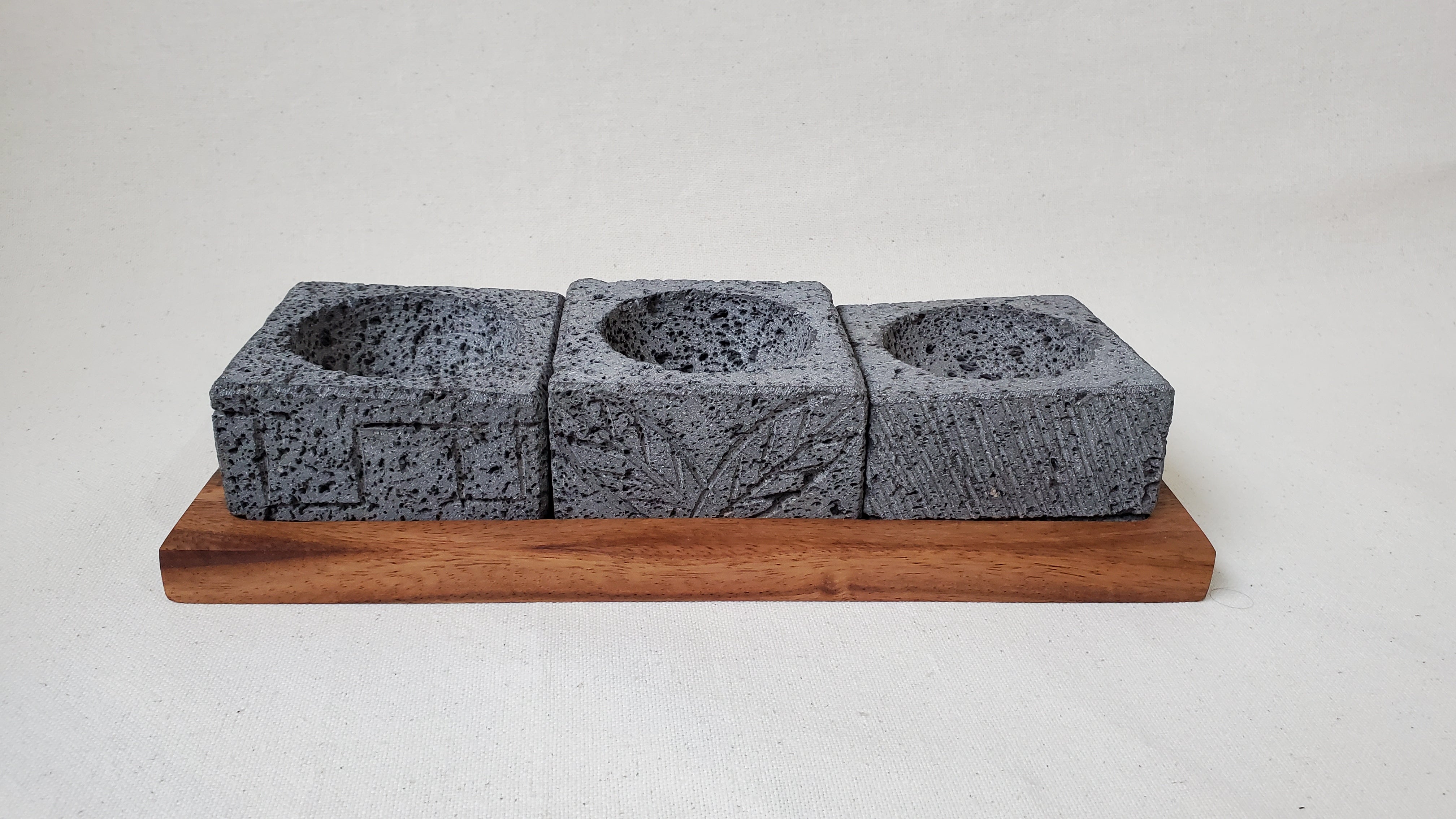 Three Square Serving Bowls on a Rectangle Wooden Base. Made of Basalt Lava Rock Volcanic Stone. Handmade in Mexico using traditional techniques. We hand finish, package, and ship from the USA. Buy now at www.felipeandgrace.com.
