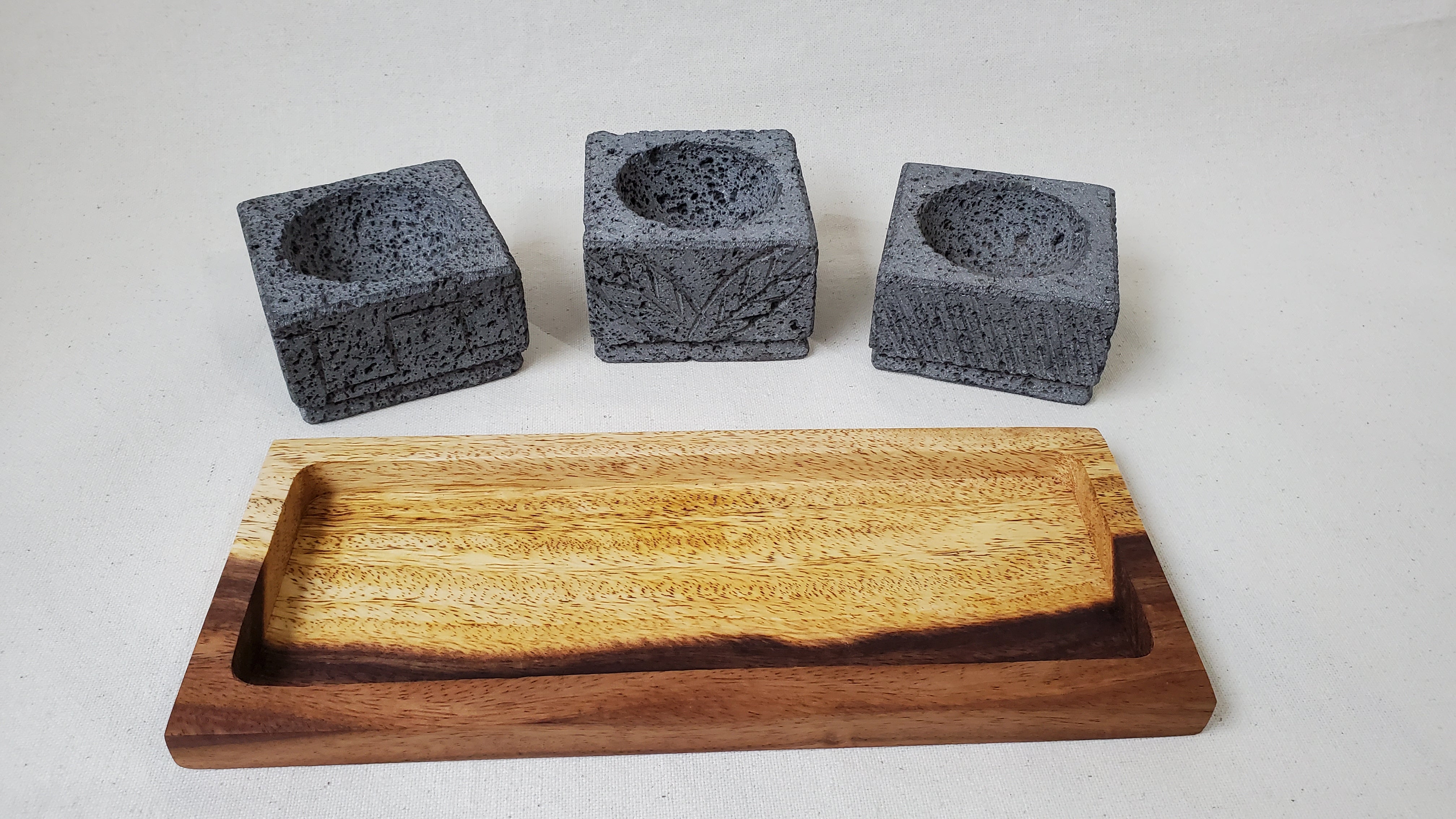 Three Square Serving Bowls on a Rectangle Wooden Base. Made of Basalt Lava Rock Volcanic Stone. Handmade in Mexico using traditional techniques. We hand finish, package, and ship from the USA. Buy now at www.felipeandgrace.com.