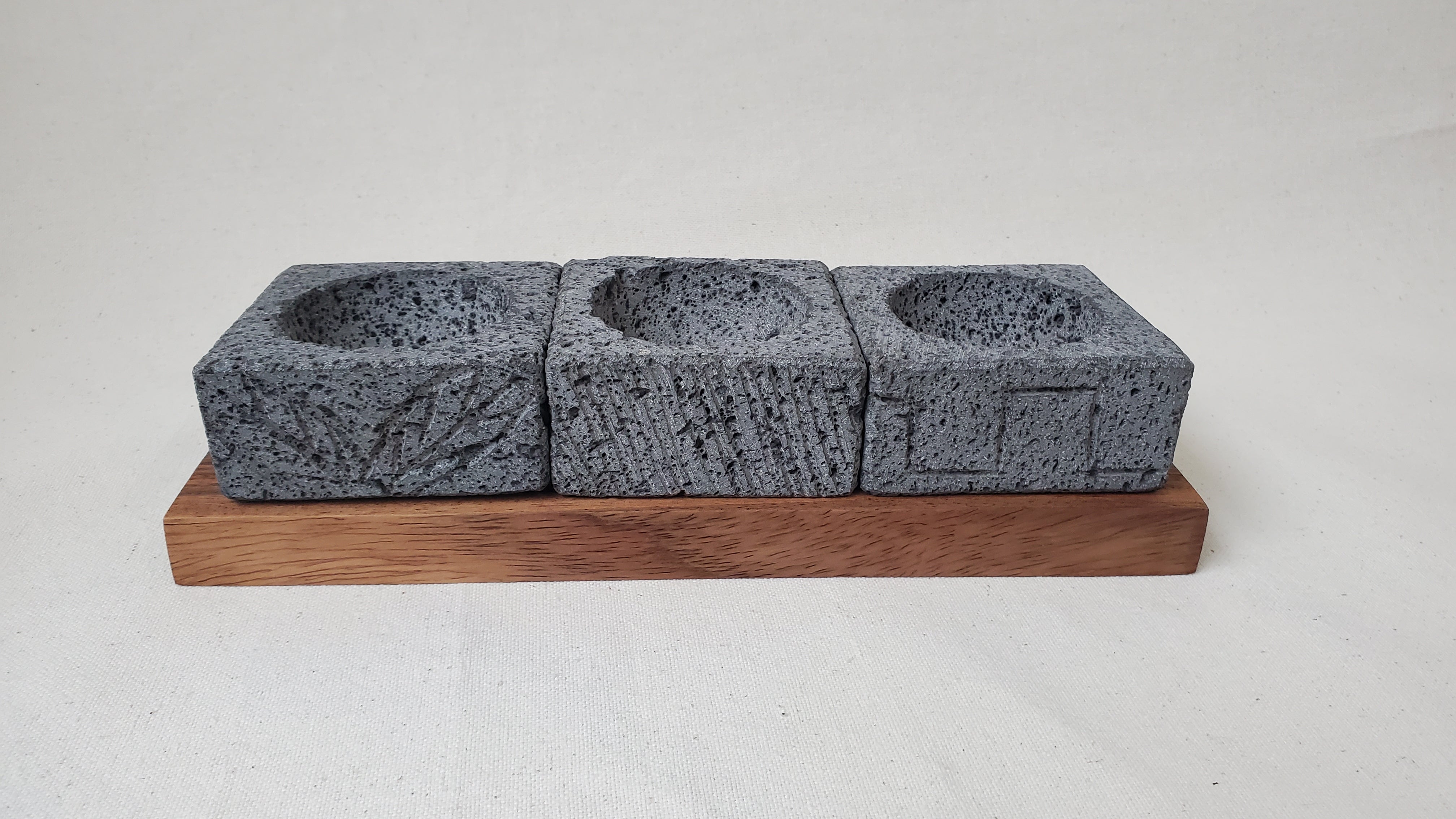 Three Square Serving Bowls on a Rectangle Wooden Base. Made of Basalt Lava Rock Volcanic Stone. Handmade in Mexico using traditional techniques. We hand finish, package, and ship from the USA. Buy now at www.felipeandgrace.com.