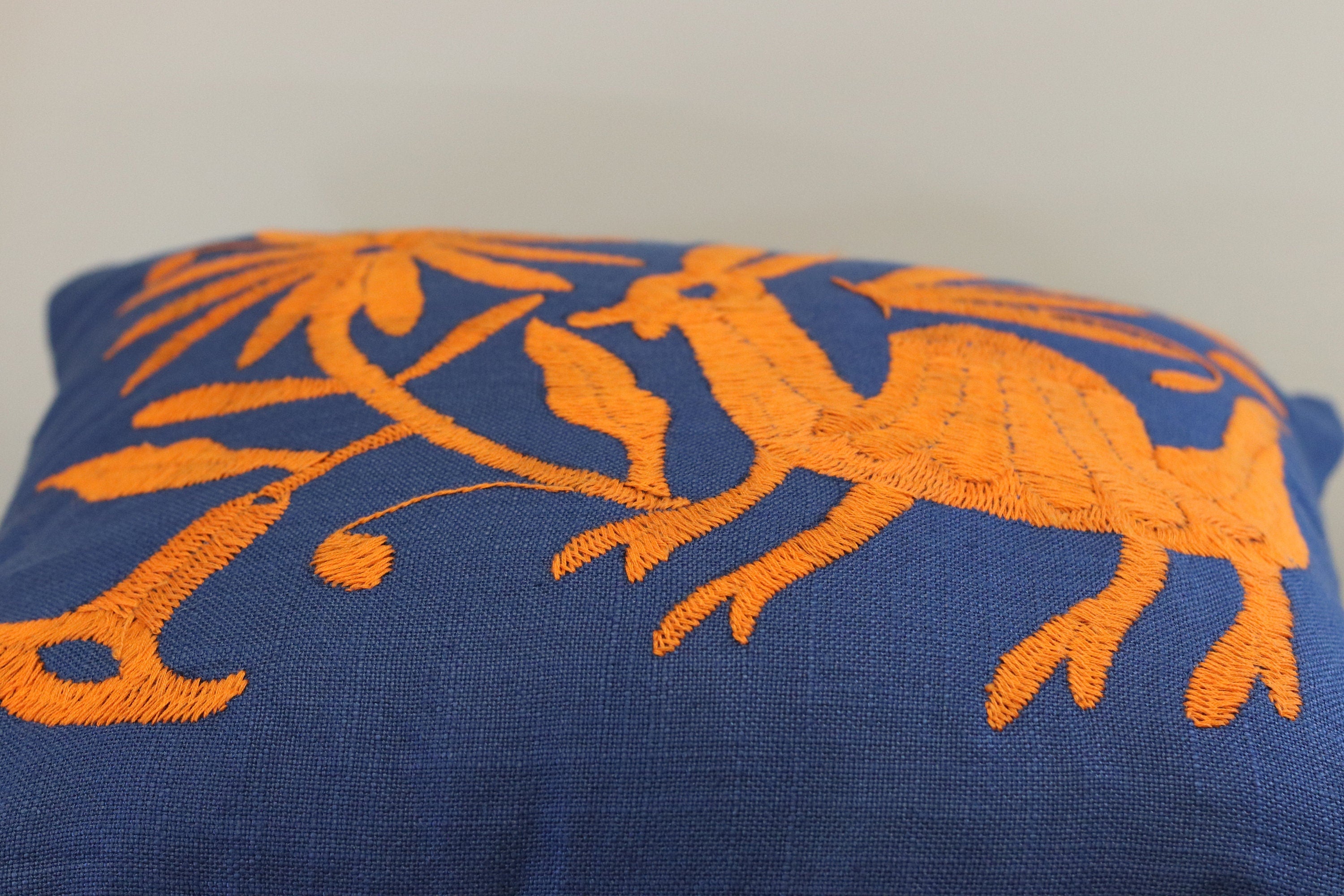 Blue and Orange Square Otomi Tenango Pillow Cover with Hand Embroidered Birds, Flowers, and Animals in Vibrant Colors. Handmade in Mexico. Ships from the USA. Buy now at www.felipeandgrace.com.