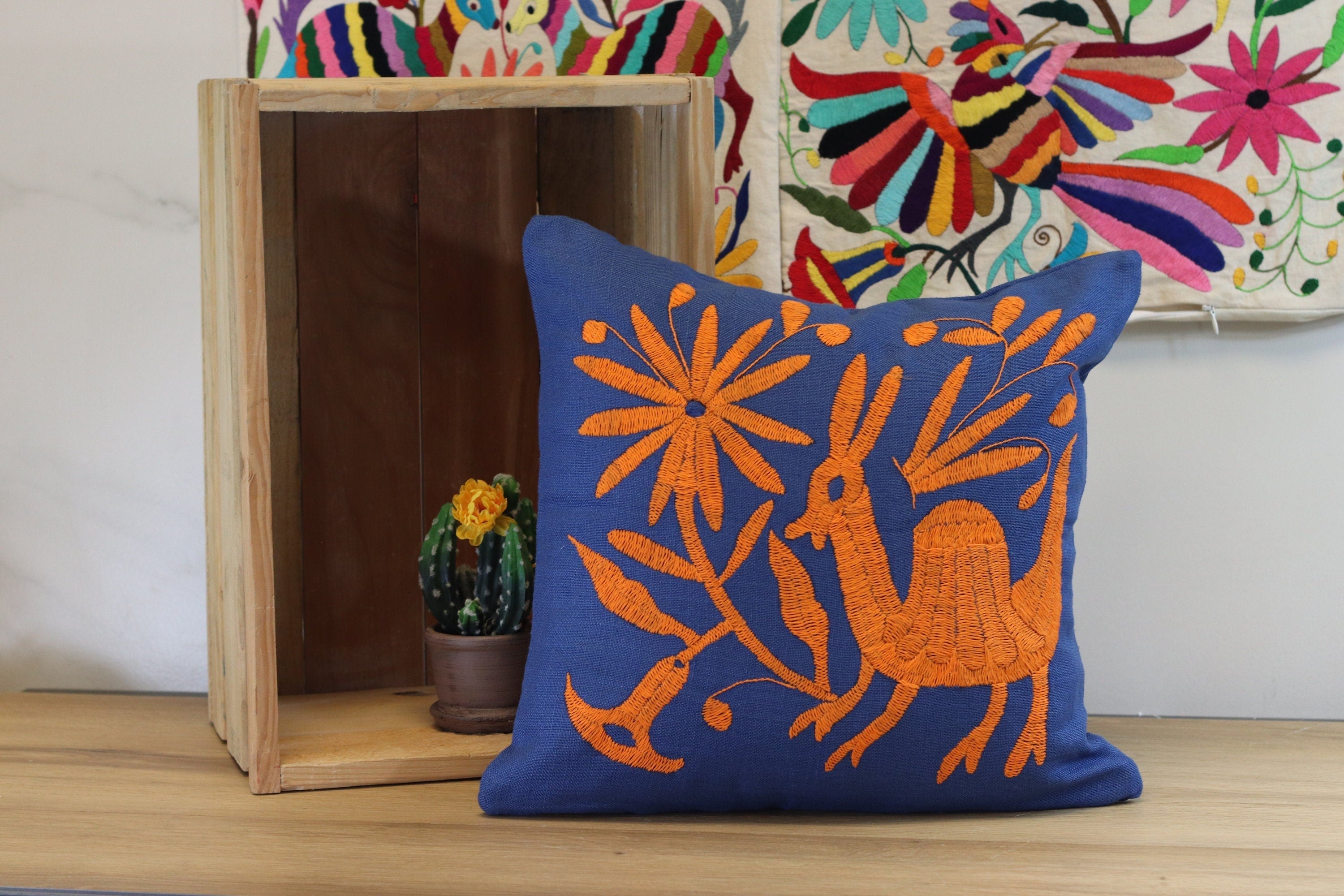 Blue and Orange Square Otomi Tenango Pillow Cover with Hand Embroidered Birds, Flowers, and Animals in Vibrant Colors. Handmade in Mexico. Ships from the USA. Buy now at www.felipeandgrace.com.